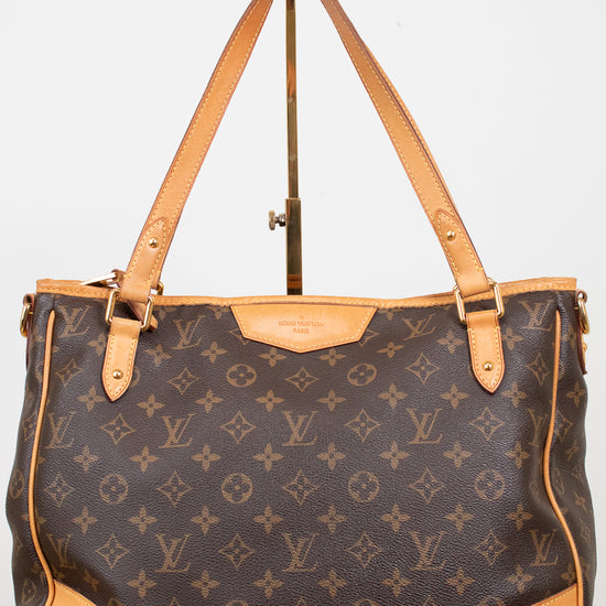 A Louis Vuitton monogram coated canvas shoulder bag with tan leather trim and handles, displayed on a stand against a light gray background.
