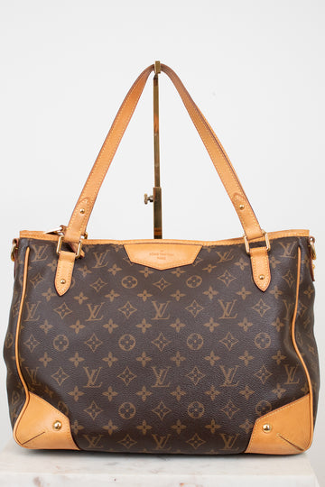 A Louis Vuitton monogram coated canvas shoulder bag with tan leather trim and handles, displayed on a stand against a light gray background.