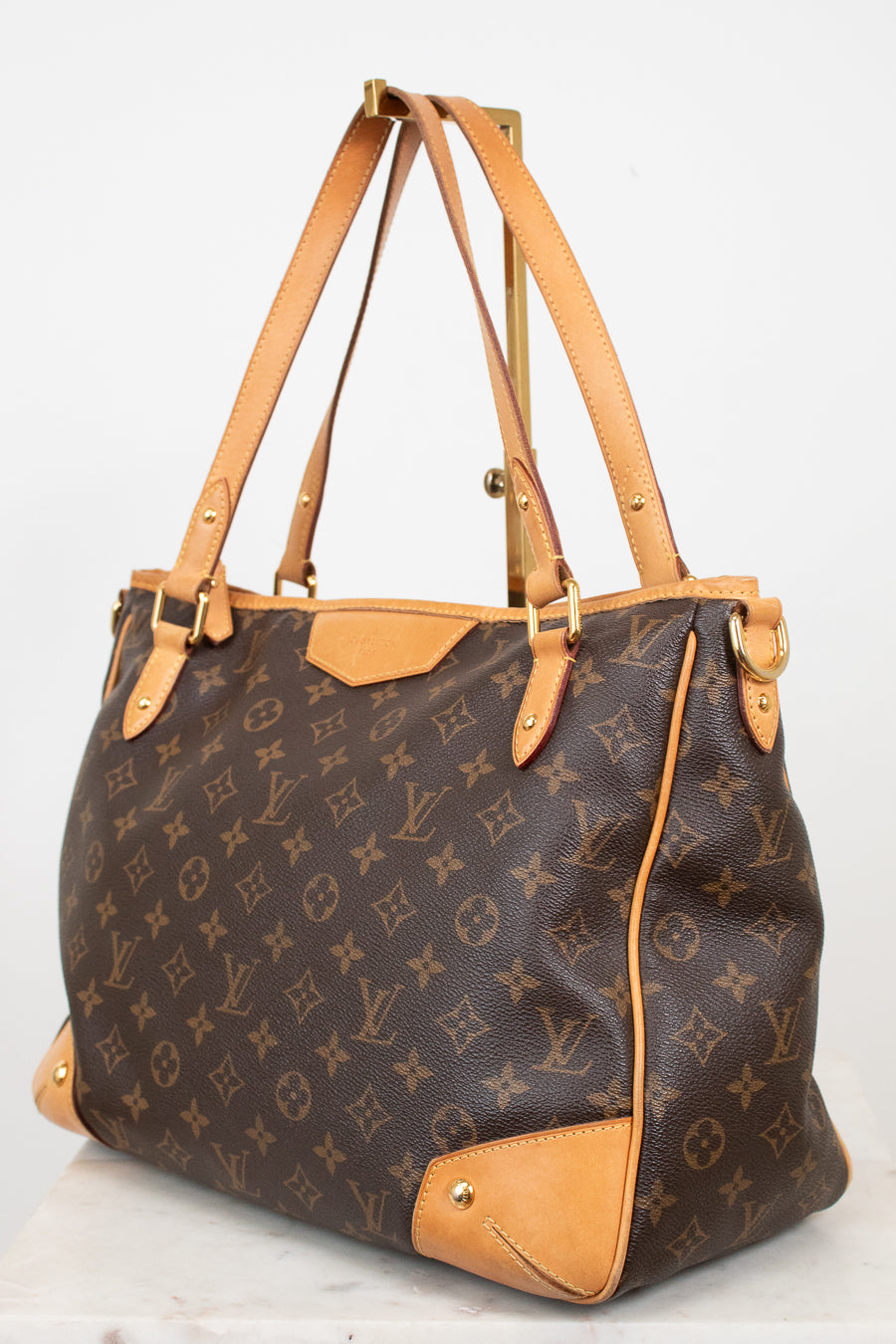 Louis Vuitton monogram canvas shoulder bag with tan leather trim and handles, displayed on a white background.