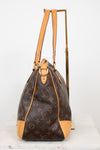 A Louis Vuitton monogram coated canvas shoulder bag with tan leather trim and gold-tone hardware, displayed on a stand against a white background.