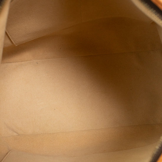 Close-up view of the interior lining of a tan leather and coated canvas bag, showing a smooth beige fabric interior with stitched compartments.