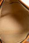 Close-up view of the interior lining of a tan leather and coated canvas bag, showing a smooth beige fabric interior with stitched compartments.