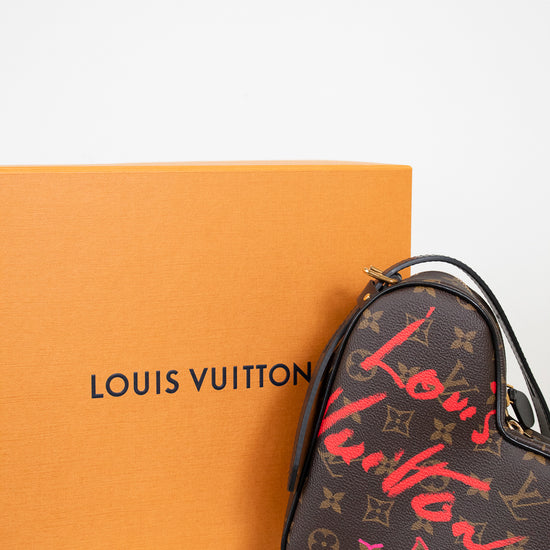 Louis Vuitton handbag with red and gold monogram pattern next to an orange box on a white background