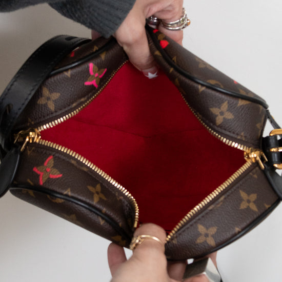 Person holding a brown leather handbag with red interior