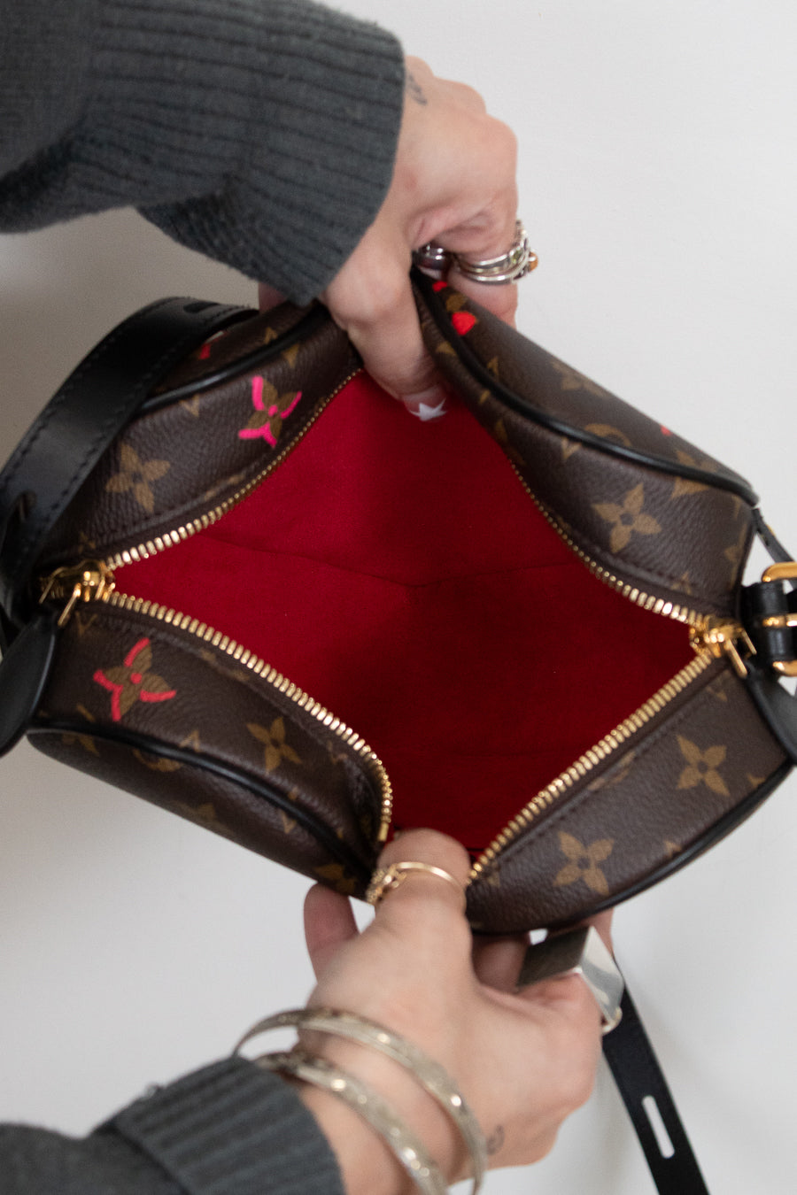 Person holding a brown leather handbag with red interior