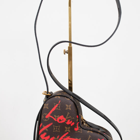 Heart-shaped handbag with Louis Vuitton monogram and red graffiti-style text on a white background.