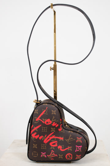 Heart-shaped handbag with Louis Vuitton monogram and red graffiti-style text on a white background.