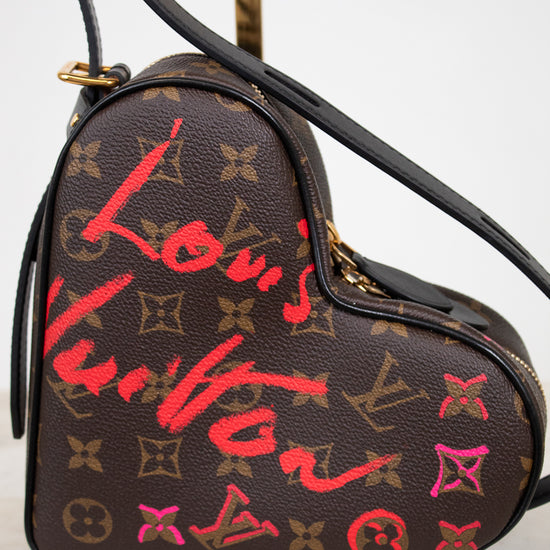 Heart-shaped Louis Vuitton bag with red and pink graffiti-style text on a white background