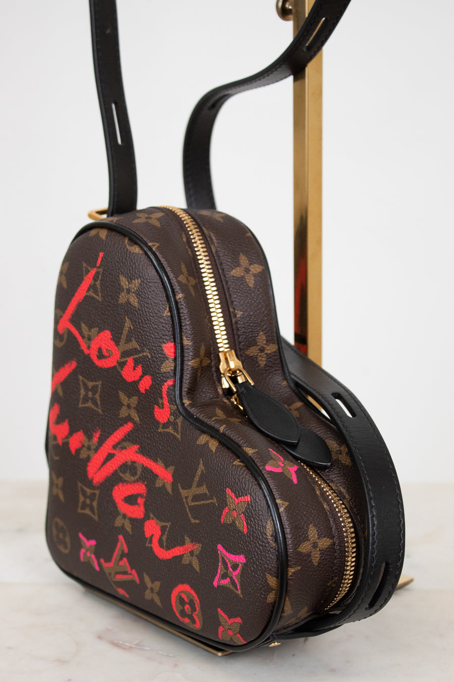 Designer handbag with monogram pattern and colorful text on a white background