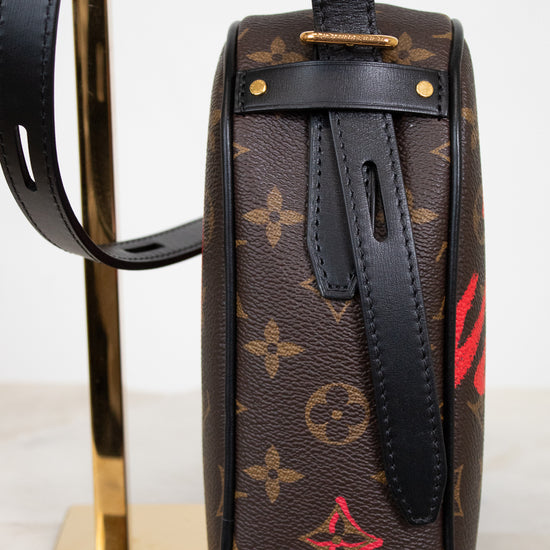 Designer handbag with monogram pattern on a stand against a white background