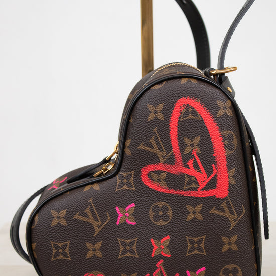 Heart-shaped handbag with monogram pattern and red heart design on a white background