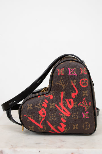 Heart-shaped handbag with Louis Vuitton monogram and graffiti-style text on a white background