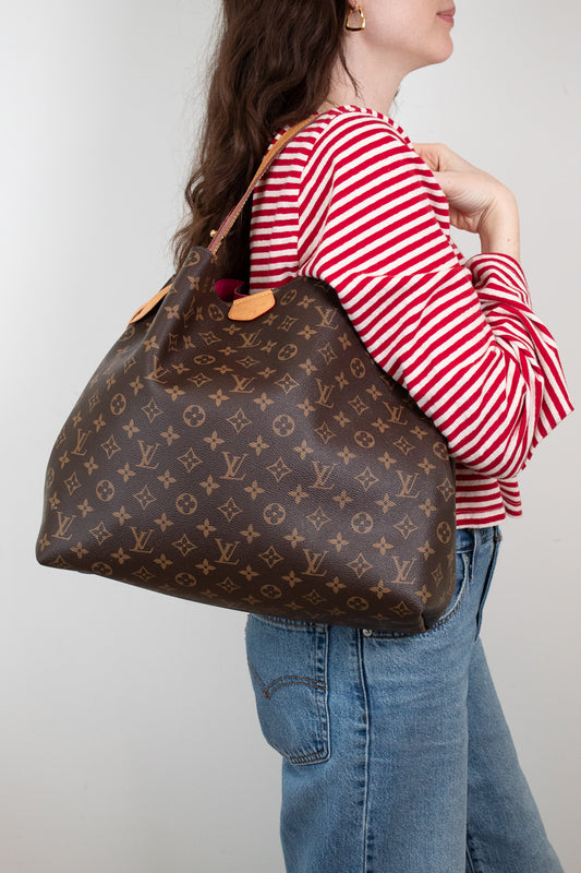 Person wearing a red and white striped shirt with a brown patterned handbag on a plain background