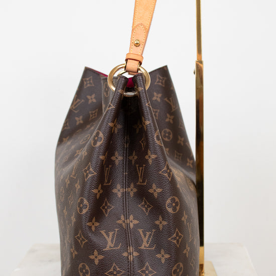 Louis Vuitton monogram handbag on a stand against a white background