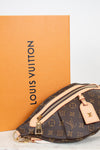 Louis Vuitton monogram bum-bag in brown coated canvas with beige leather trim and gold-tone hardware, shown in front of an orange Louis Vuitton box on a white surface.
