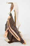 Louis Vuitton monogram coated canvas sling bag with beige leather trim and a wide cream canvas shoulder strap, displayed on a gold stand against a white background.