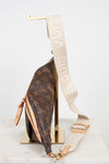 Louis Vuitton monogram shoulder bag in brown coated canvas with a beige canvas strap featuring white 'LOUIS VUITTON' text, displayed on a gold stand against a white background.