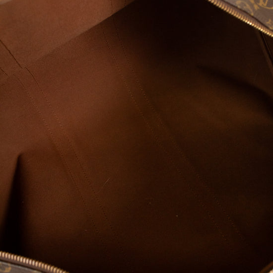 Hand wearing red nail polish holding open monogrammed bag showing brown textile interior