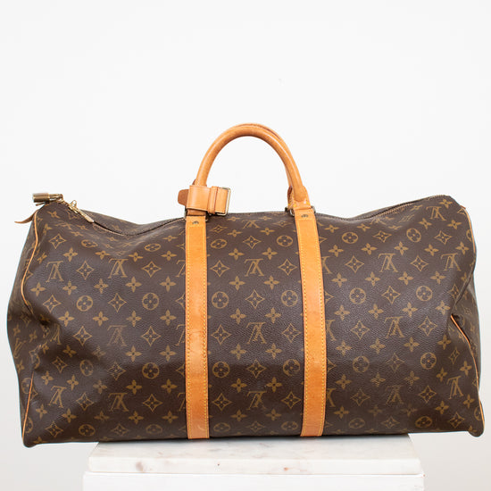Large monogrammed duffel bag with leather trim details on white stand against light background