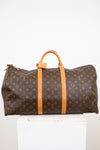 Large monogrammed duffel bag with leather trim details on white stand against light background