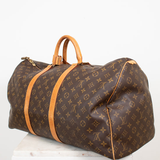 Large monogram coated canvas and tan leather duffel bag on white stand with light background