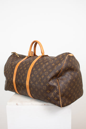 Large monogram coated canvas and tan leather duffel bag on white stand with light background