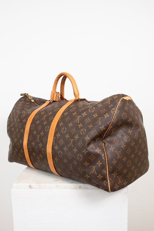 Large monogram coated canvas and tan leather duffel bag on white stand with light background