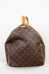 Side view of monogram duffel bag with visible rip of tan leather tab shown and tan leather handles showing against a light background