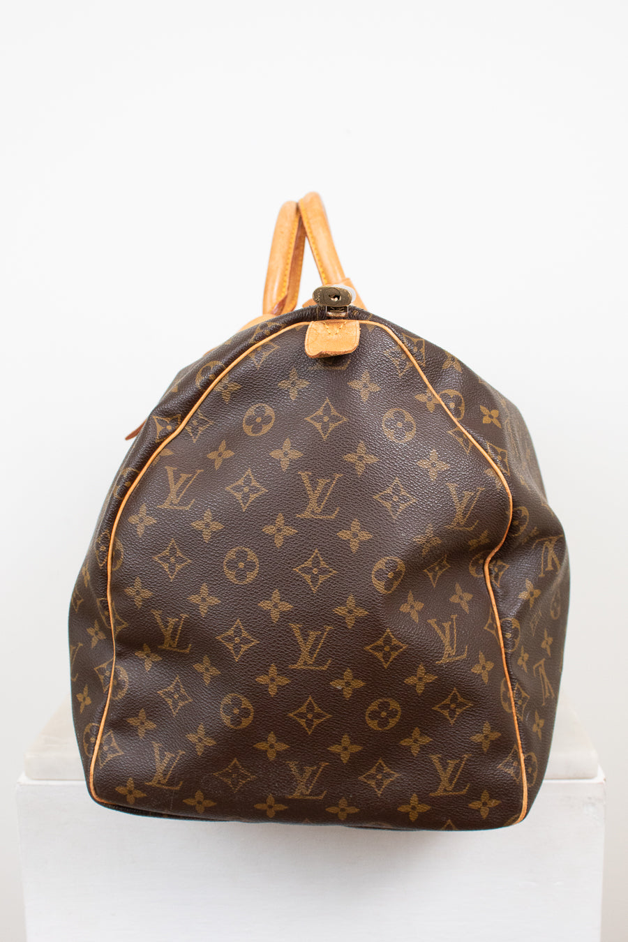 Side view of monogram coated canvas with leather trim details against a light background