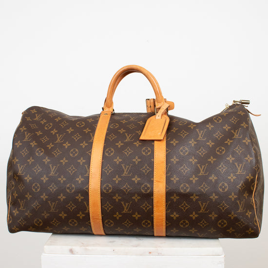 Large monogrammed duffel bag on white stand and against a light background