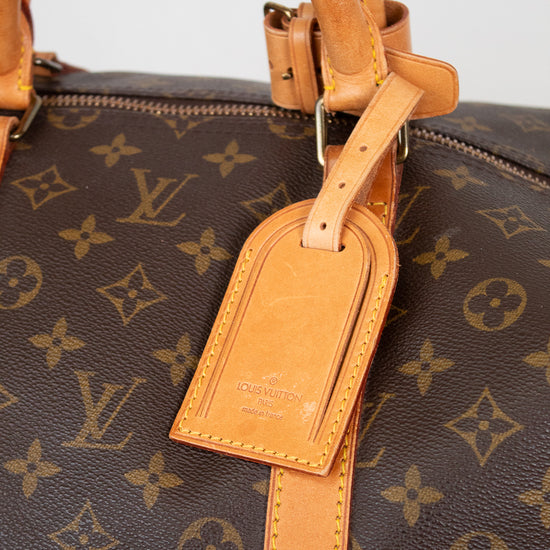 Close-up of tan leather tab with 'Louis Vuitton' branding visible attached to monogram coated canvas 