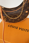 Louis Vuitton handbag with monogram pattern and gold chain on an orange Louis Vuitton box.