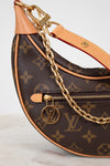 Louis Vuitton handbag with monogram pattern and gold chain on a light background