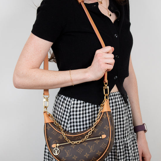 Person wearing a black top and checkered skirt with a brown handbag.