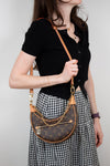 Person wearing a black top and checkered skirt with a brown handbag.