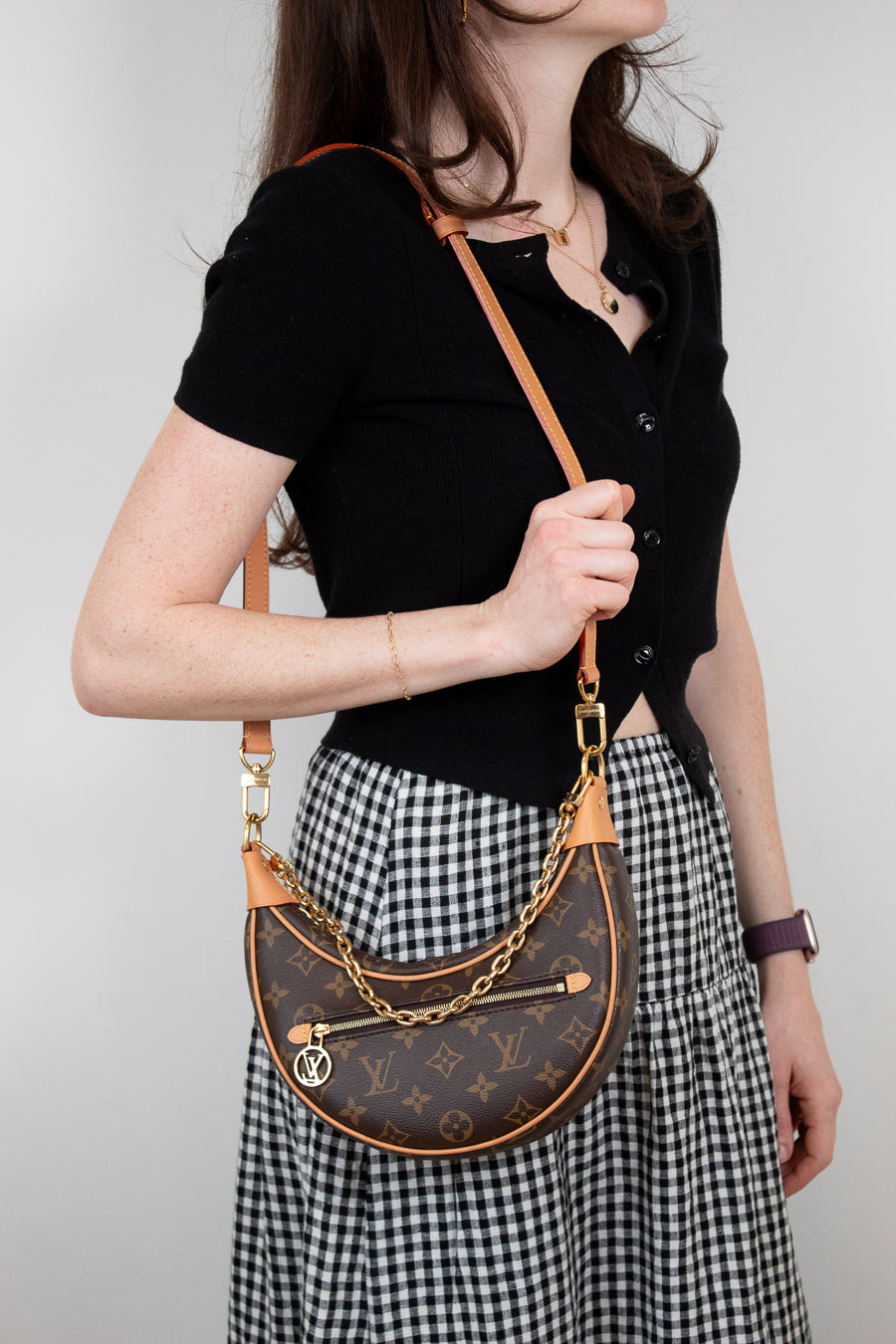 Person wearing a black top and checkered skirt with a brown handbag.