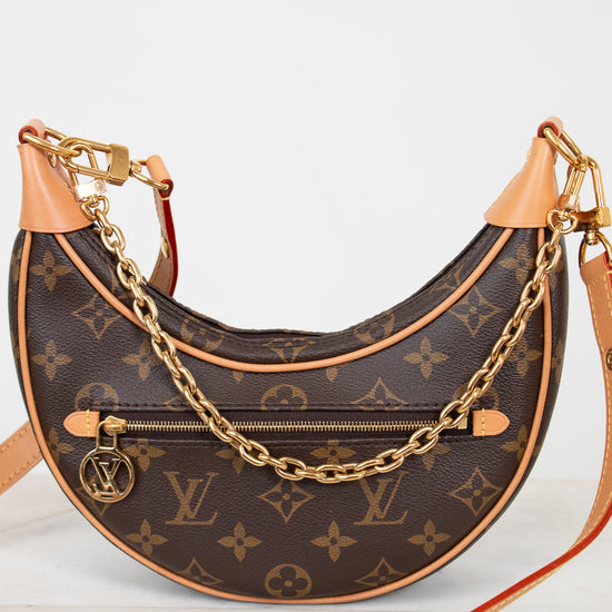 Designer handbag with monogram pattern and gold chain on a white background