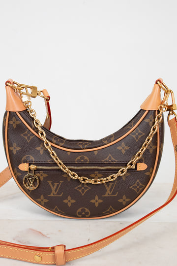 Designer handbag with monogram pattern and gold chain on a white background