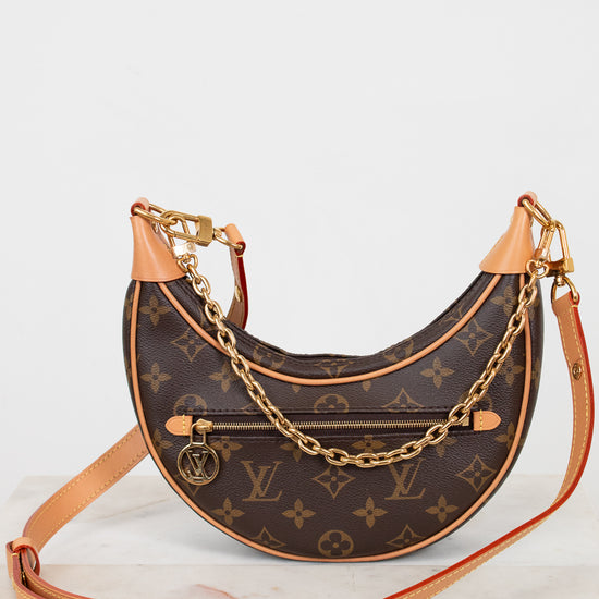 Designer handbag with monogram pattern and gold chain on a white background