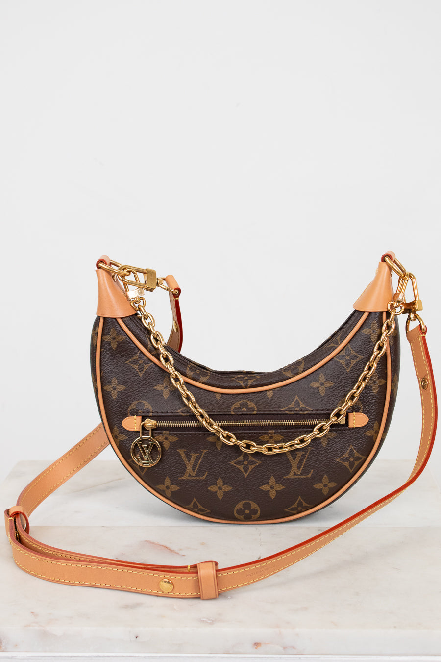 Designer handbag with monogram pattern and gold chain on a white background