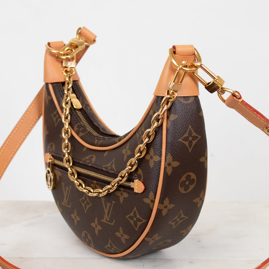 Designer handbag with monogram pattern and gold chain on a light background