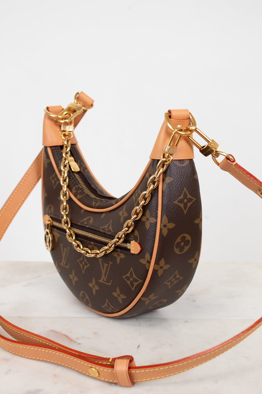 Designer handbag with monogram pattern and gold chain on a light background