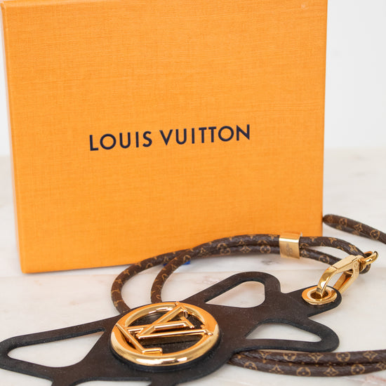 Louis Vuitton monogrammed leather star-shaped bag charm with a gold-tone LV logo medallion, shown with its signature orange Louis Vuitton box on a light marble surface.