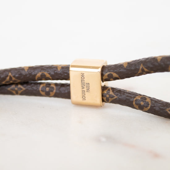 Louis Vuitton monogrammed leather bracelet with a gold-tone rectangular clasp engraved with 'LOUIS VUITTON PARIS'.