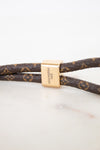 Louis Vuitton monogrammed leather bracelet with a gold-tone rectangular clasp engraved with 'LOUIS VUITTON PARIS'.