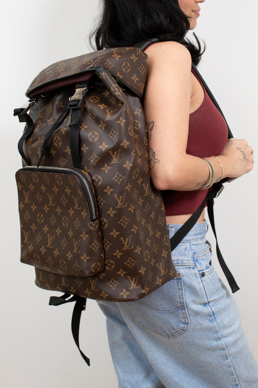 Person wearing a brown patterned backpack on a plain background