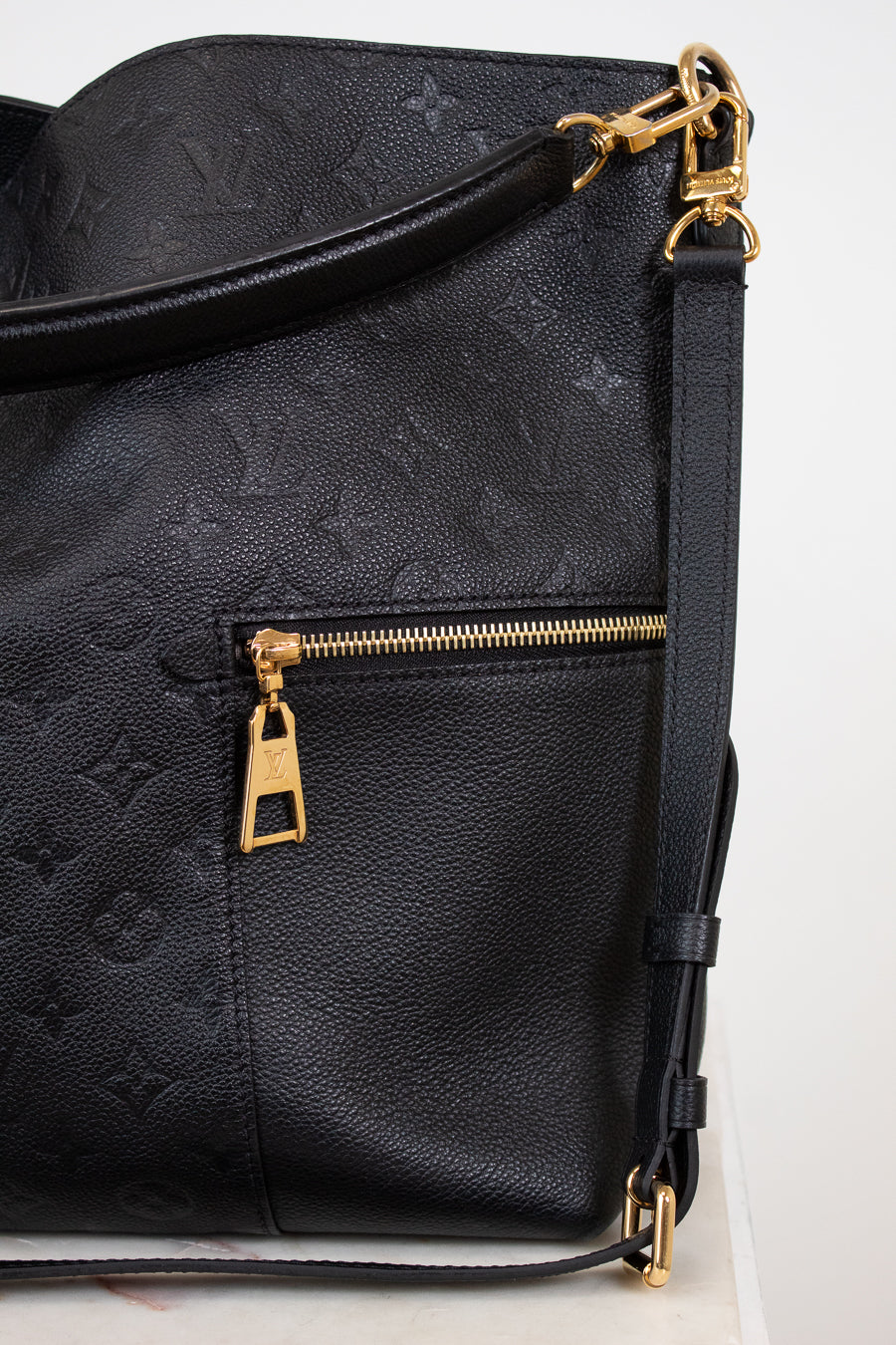Black leather bag with gold zipper and hardware on a white background