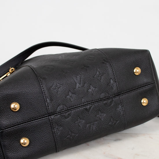Black leather handbag with gold hardware on a marble surface