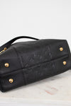 Black leather handbag with gold hardware on a marble surface