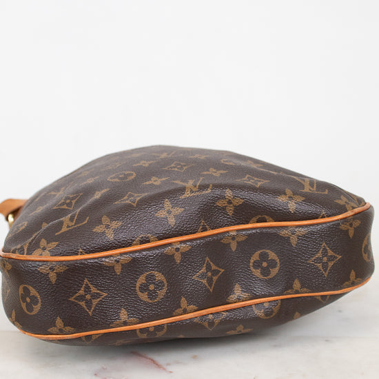 A Louis Vuitton monogram canvas shoulder bag in brown with tan leather trim, resting on a light marble surface against a white background.